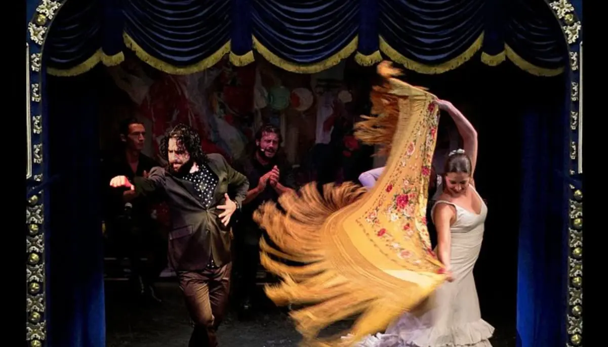Bailaora con mantón y músicos sobre el escenario del Teatro Flamenco Triana de Sevilla